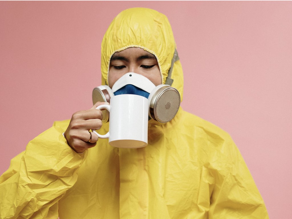 Man trying to drink coffee while wearing a ventilator